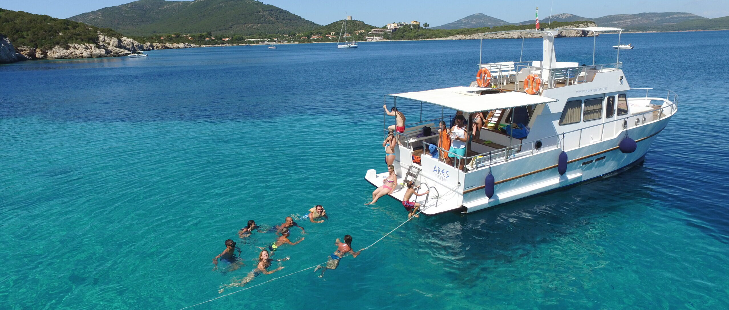 Gruppo di persone che fa il bagno durante un'escursione in barca ad Alghero con Ares Turismo.