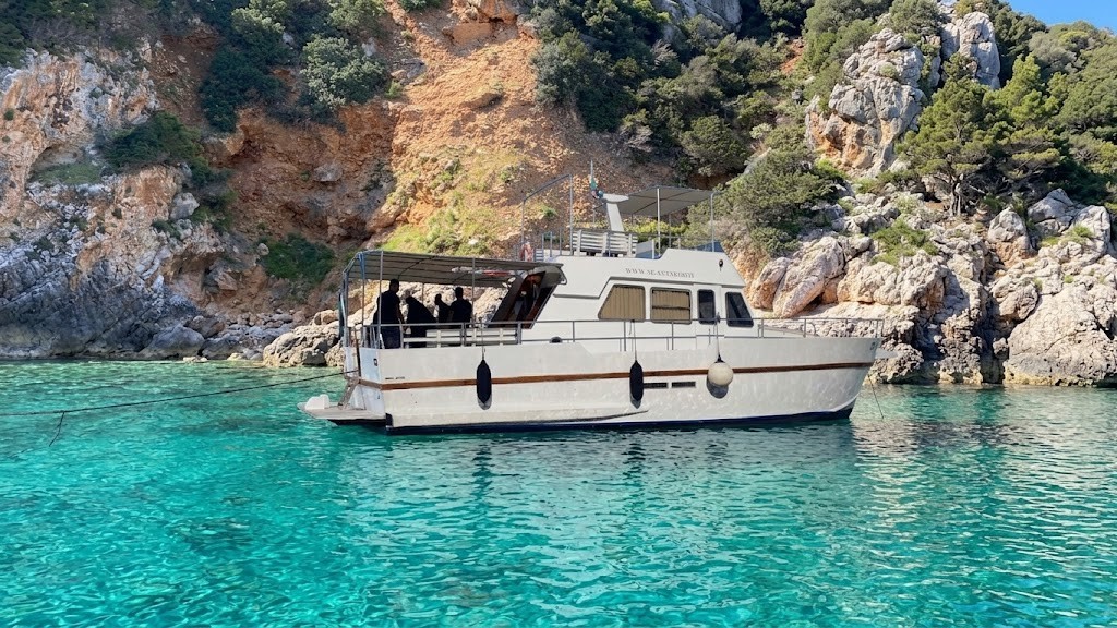 Barca bianca durante un'escursione in barca ad Alghero vicino a una scogliera con acqua cristallina.