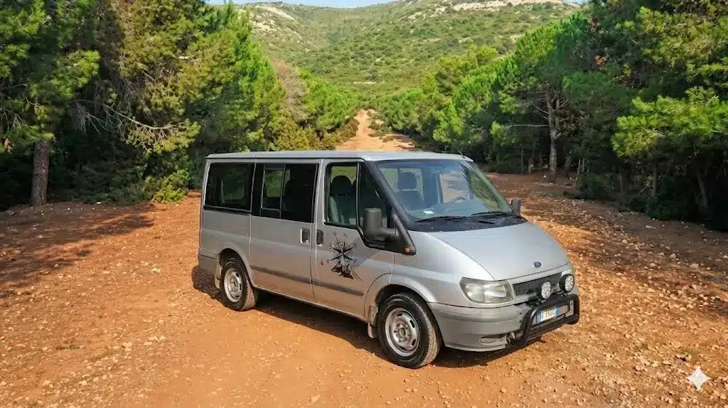 Tavola imbandita in un agriturismo tipico ad Alghero, con piatti di pasta fresca (malloreddus o culurgiones), taglieri di salumi e formaggi sardi, pane carasau e vino rosso.