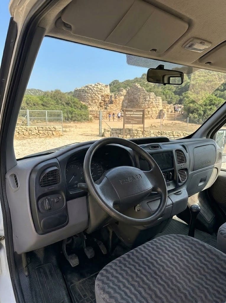 Vista dall'interno di un furgone verso il sito archeologico Nuraghe Palmavera durante un tour in van ad Alghero.